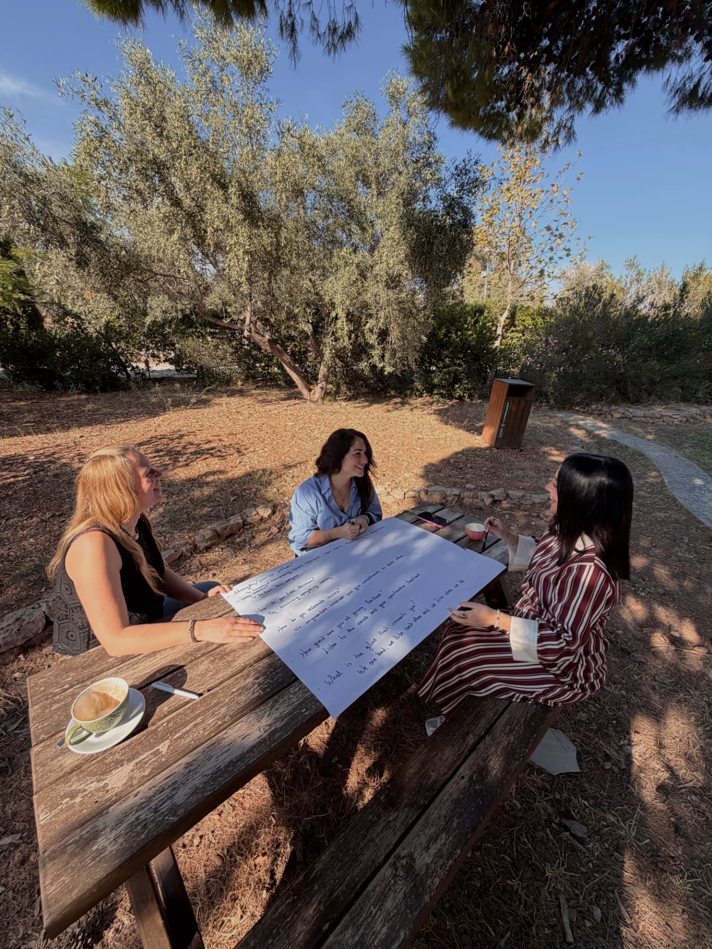 Three MindWavers filling in a poster board at a picnic table in a park