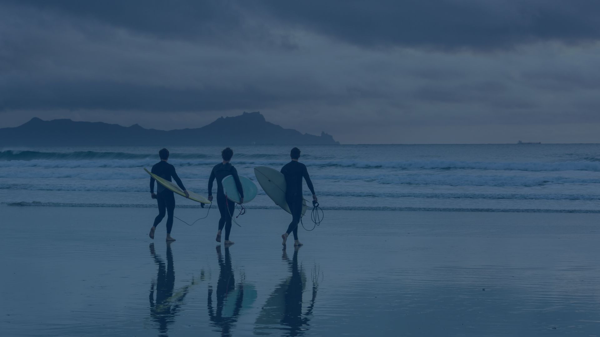 Professionals carrying surfboards toward the sea
